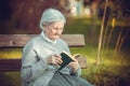 Portrait of senior woman in park reading book