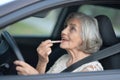 Portrait of senior woman putting lipstick in the car Royalty Free Stock Photo