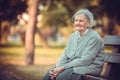 Portrait of senior woman sitting on bench in autumn park. Old lady feeling lonely and sad