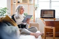 Portrait of senior woman sitting indoors on sofa at home, using tablet. Royalty Free Stock Photo