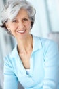 Portrait of senior woman smiling with healthy white teeth. Beautiful old female standing alone inside a room. Happy Royalty Free Stock Photo