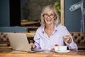 Portrait of senior woman using laptop computer while eating breakfast Royalty Free Stock Photo