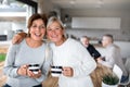 Portrait of senior women friends with coffee at home, looking at camera.