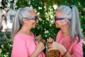 Portrait of senior women twins looking each other outdoor, side view.