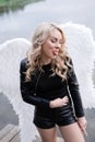 portrait of a sensitive woman with white angel wings. wearing black leather clothes. fallen dark angel. demon. beast. Royalty Free Stock Photo