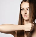 Portrait of sensual young woman holding strand of her long silky hair in her fist demonstrating it strength and health