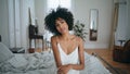 Portrait serene lady sitting bed. Curly brunette woman touching soft skin posing Royalty Free Stock Photo