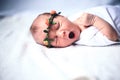 Serene newborn baby on a bed yawning