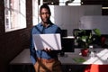 Portrait of serious african american businessman standing in office holding laptop Royalty Free Stock Photo