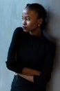 Portrait of a serious african or black american woman with arms folded standing over gray background and looking away Royalty Free Stock Photo