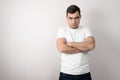 Portrait of a serious, angry young man with folded arms in a white t-shirt with a copy of space Royalty Free Stock Photo