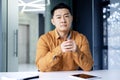 Portrait of a serious Asian office worker sitting at a desk in a bright office and talking on a video call, a Chinese Royalty Free Stock Photo