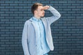 Portrait of serious attentive handsome young blonde man in casual style standing with hand on forehead and looking away to find Royalty Free Stock Photo