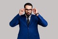 Bearded businessman putting off eyeglasses and looking at camera with bossy expression. Royalty Free Stock Photo