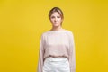 Portrait of serious beautiful young woman with fair hair in casual beige blouse, isolated on yellow background Royalty Free Stock Photo