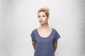 Portrait of serious blonde girl looking directly in camera cross her hands back. Wearing casual blue t-shirt. Royalty Free Stock Photo