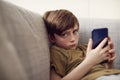 Portrait Of Serious Boy Sitting On Sofa At Home Gaming On Hand Held Devices At Home Royalty Free Stock Photo