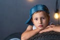 Portrait serious boy 7 years old, ileaning on the tire of a car in garage Royalty Free Stock Photo