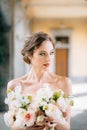 Portrait of a serious bride with her head turned in a dress with a bouquet of pink flowers in a vaulted room. Lake Como