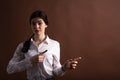 Portrait of serious brunette business woman pointing her finger to the side in studio on brown background with copyspace. Royalty Free Stock Photo