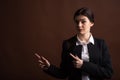 Portrait of serious brunette business woman pointing her finger to the side in studio on brown background with copyspace. Royalty Free Stock Photo