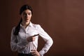 Portrait of serious brunette business woman pointing her finger to the side in studio on brown background with copyspace. Royalty Free Stock Photo