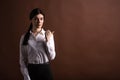 Portrait of serious brunette business woman pointing her thumb to the side in studio on brown background with copyspace. Royalty Free Stock Photo