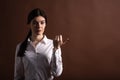 Portrait of serious brunette business woman pointing her thumb to the side in studio on brown background with copyspace. Royalty Free Stock Photo