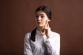 Portrait of a serious brunette business woman who thinks with her finger to her face in the studio on a brown background. Royalty Free Stock Photo