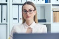 Portrait of young serious businesswoman looking at the camera while using laptop in office. Royalty Free Stock Photo