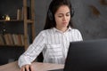 Portrait of a serious casual businesswoman sitting at the table with laptop in home office and looking at screen pc Royalty Free Stock Photo