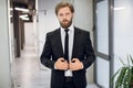 Portrait of a serious Caucasian bearded man office worker, wearing elegant formal black suit, posing to camera while Royalty Free Stock Photo