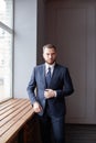 Portrait of serious clever businessman in suit standing in his office