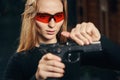 Focused experienced young woman reloading a handgun