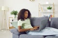 Serious young african teenager girl using laptop lying on sofa at home. Royalty Free Stock Photo