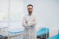 Portrait of a serious confident male doctor standing with arms crossed at medical office Royalty Free Stock Photo