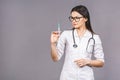 Portrait of serious female doctor in medical mask holding syringe for injection isolated on grey background Royalty Free Stock Photo