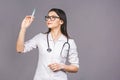 Portrait of serious female doctor in medical mask holding syringe for injection isolated on grey background Royalty Free Stock Photo