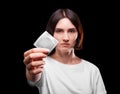 A close-up of a serious young woman showing a packed condom on a black background. Healthy lifestyle concept. Copy space