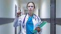 Portrait of serious female medical doctor or nurse with stethoscope in the hospital corridor and showing attention sign. Royalty Free Stock Photo