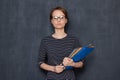 Portrait of serious focused girl with glasses, holding folders and pen Royalty Free Stock Photo