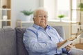 Portrait of a serious focused senior man sitting on the couch and reading an interesting book. Royalty Free Stock Photo