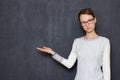 Portrait of serious focused young woman pointing at copy space on left Royalty Free Stock Photo