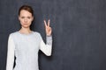 Portrait of serious focused young woman showing peace gesture Royalty Free Stock Photo