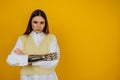 Portrait of a serious girl with a bionic prosthetic arm in a white shirt looking at the camera on a yellow background Royalty Free Stock Photo