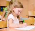 Portrait of a serious girl who writes in a exercise book during Royalty Free Stock Photo