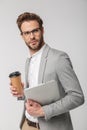 Portrait of serious handsome man posing with laptop and paper cup Royalty Free Stock Photo