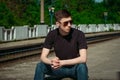 Portrait serious handsome young man sitting on a step at railway station Royalty Free Stock Photo