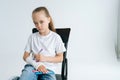 Portrait of serious little girl drawing cute image with colorful marker on broken arm wrapped in white plaster bandage