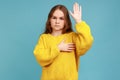 Portrait of serious little girl raising her palm to take oath, child swearing to tell only truth.